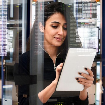 Woman with a tablet standing in a data centre. 