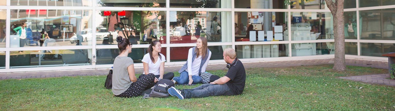 Students sitting on green grass on campus setting