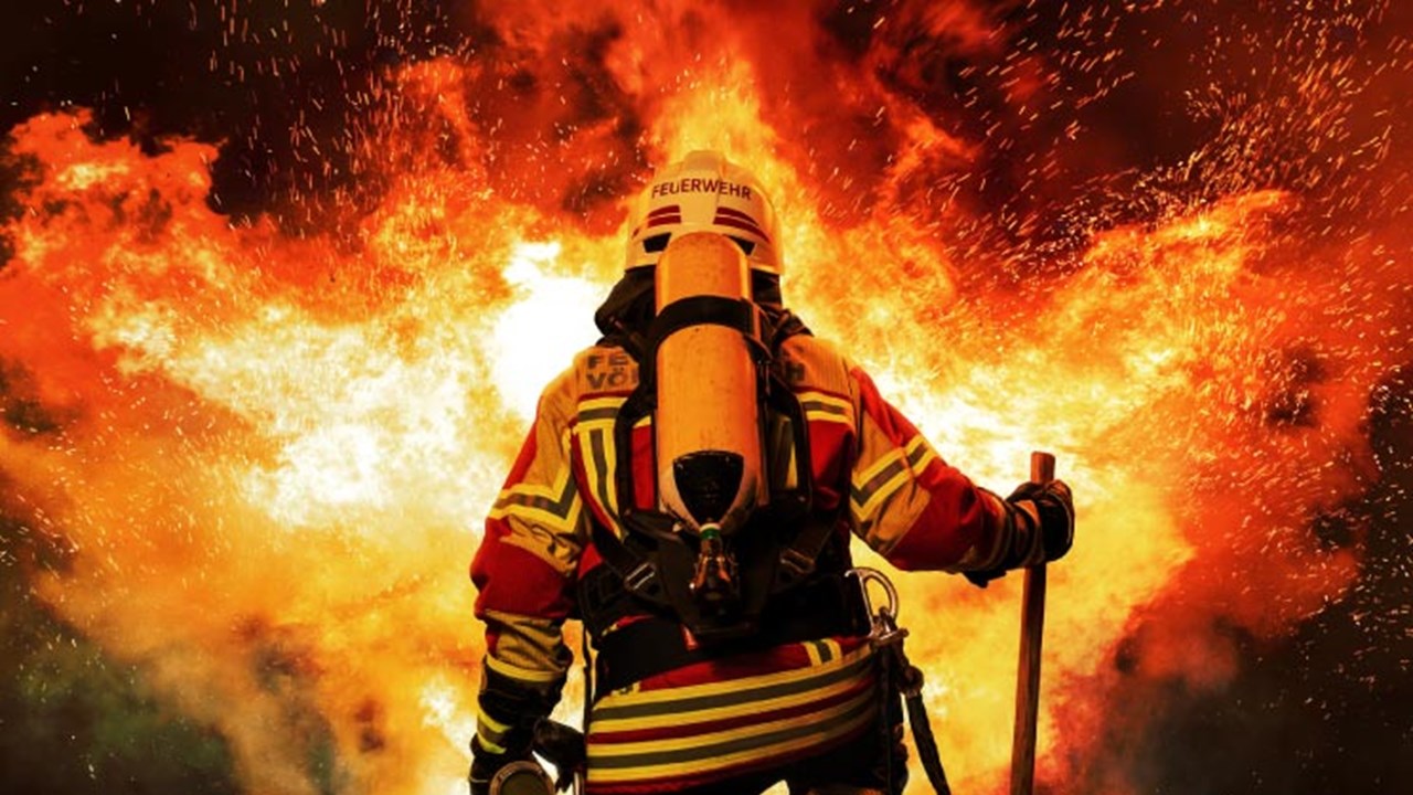 A firefighter kneels before the fire.