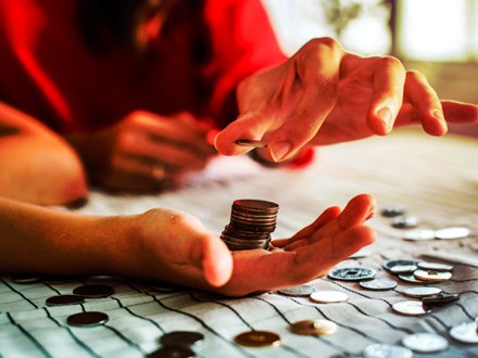 Woman's hands counting coins on a table.