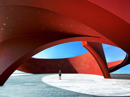 A person standing in a red curved abstract architectural space, 3D rendering.