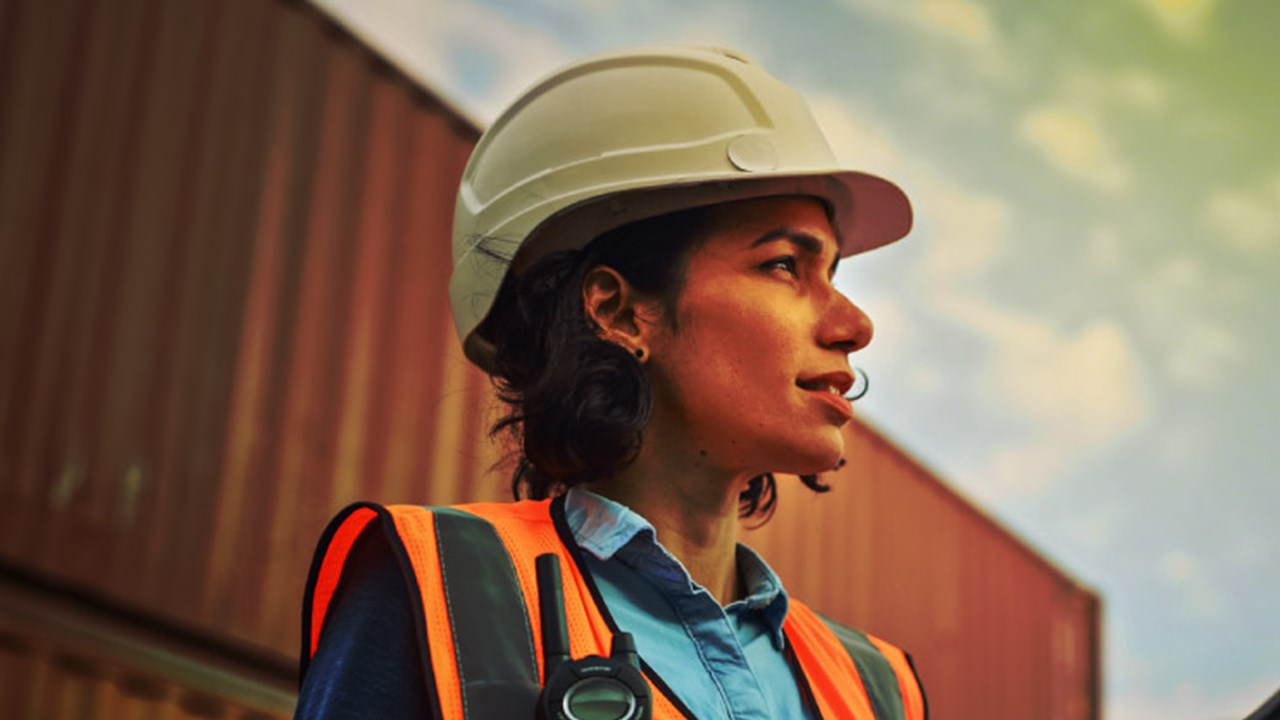 Smiling Portrait of a Beautiful Latin Female Industrial Engineer in White Hard Hat, High-Visibility Vest Working on Tablet Computer.