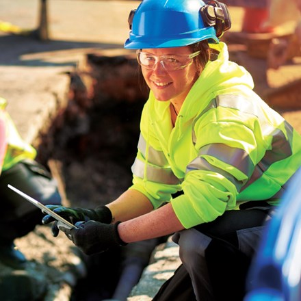 A female gas engineer holds a new gas valve as she and a colleague prepare to replace the old pipework in a residential UK street .