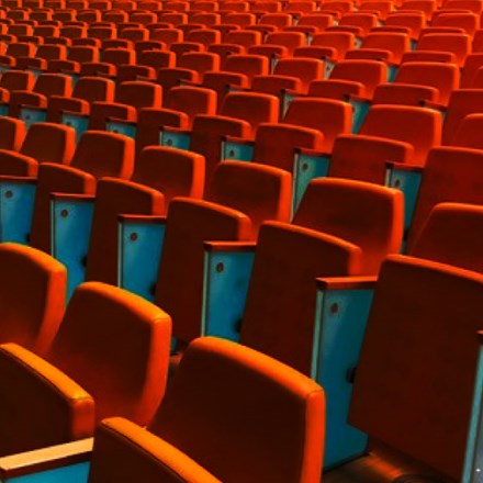Rows and rows of empty orange auditorium chairs.