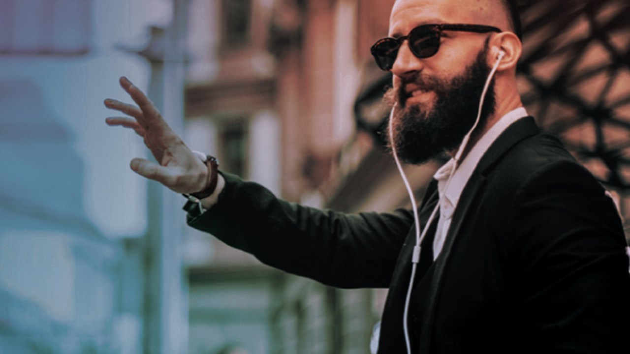 Bearded guy with headphones on, signalling to someone to talk about their ERP system.   